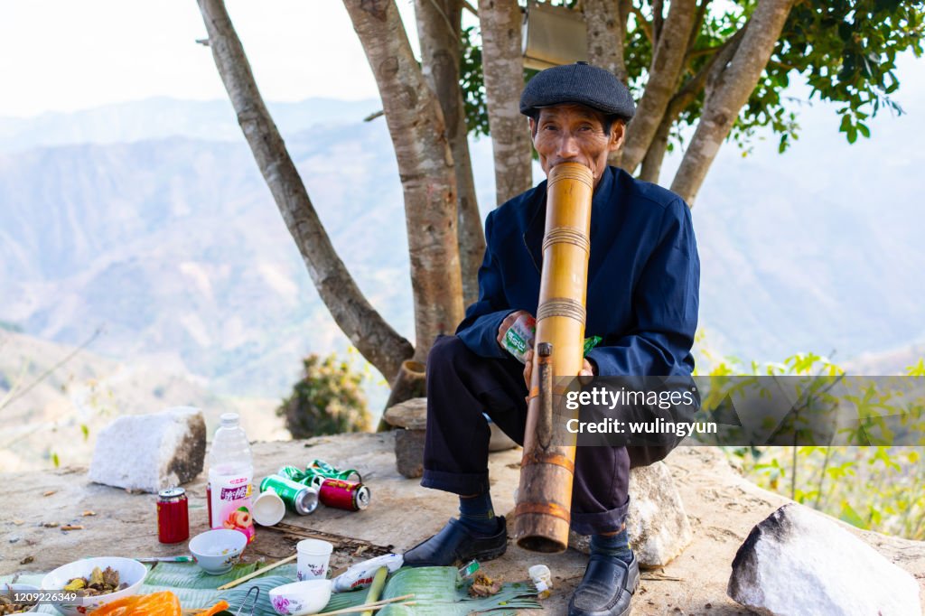A Chinese senior man smoking with bamboo water pipe