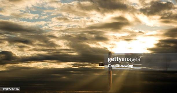 cross and dramatic sky with sun rays and dark clouds - cross shape stock pictures, royalty-free photos & images