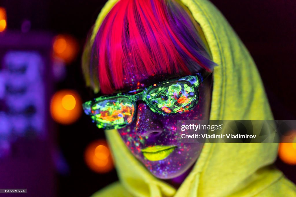 Woman with neon makeup powder on face and colored sunglasses