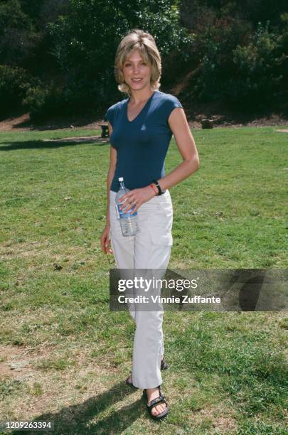 American actress Marla Maples wearing a blue cap-sleeve top and white trousers, holding a water bottle, circa 1995.