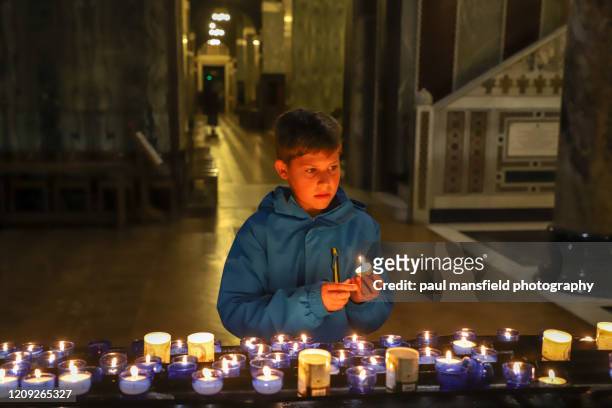 boy holding prayer candle in church - child praying stock pictures, royalty-free photos & images