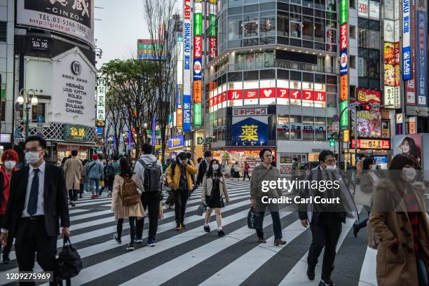 People cross a road near the Kabuki-cho adult entertainment district of Tokyo, an area that has seen a disproportionate number of Covid-19...