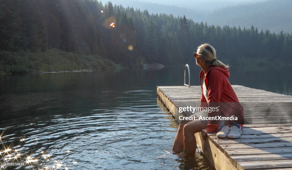 La donna matura si rilassa sul molo di legno, si affaccia sul lago