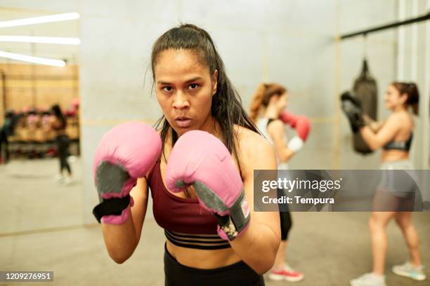 jonge spaanse vrouw in het vechten houding en het bekijken van camera. - woman gym boxing stockfoto's en -beelden