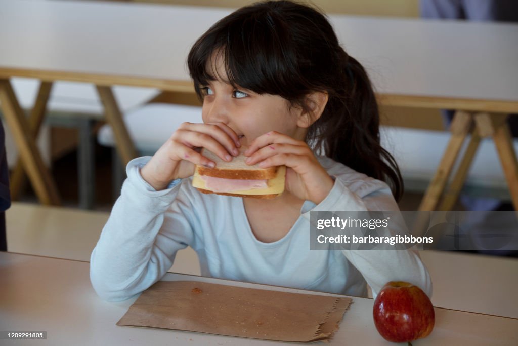 Una chica en la escuela almorzando.