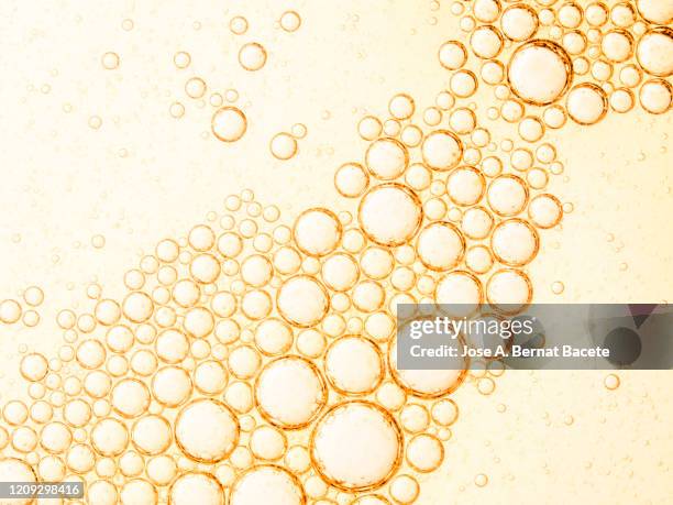 full frame of abstract shapes and textures formed of bubbles and drops oil stains on a yellow color liquid background. - oil flow stockfoto's en -beelden