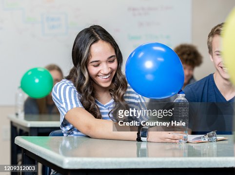 Female high school student performing science experiment in class