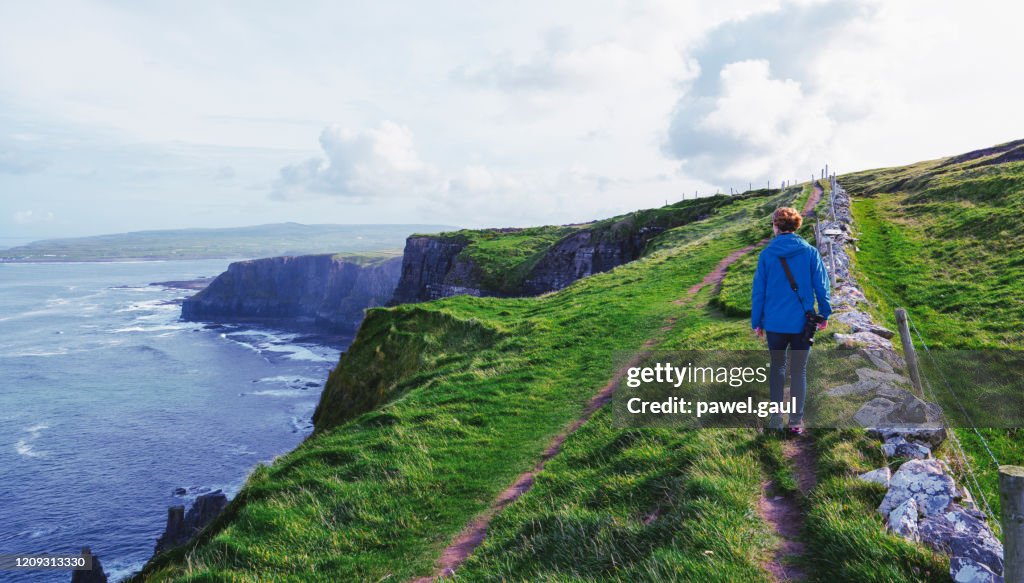 Woman hiking on Cliffs of Moher walking trail in Ireland