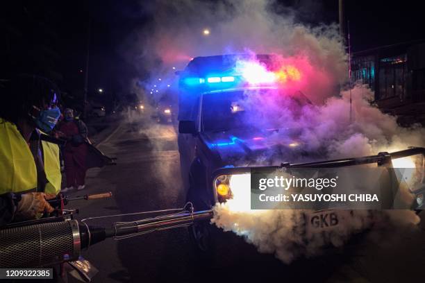 Volunteer from Sonko Rescue Team, an NGO privately funded by Nairobi Governor Mike Sonko, fumigates a police car to curb the spread of COVID-19...