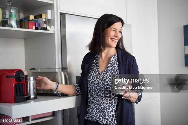 smiling woman preparing coffee in a domestic kitchen - kaffeemaschine stock-fotos und bilder