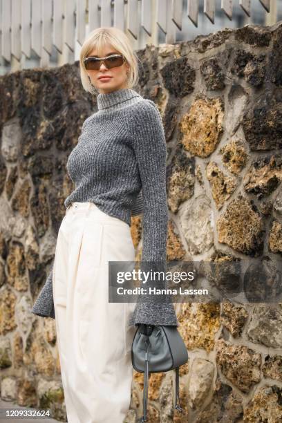 Xenia Adonts wearing grey knit scarf, jumper, white boots and beige joggers outside the Loewe show during the Paris Fashion Week Womenswear...