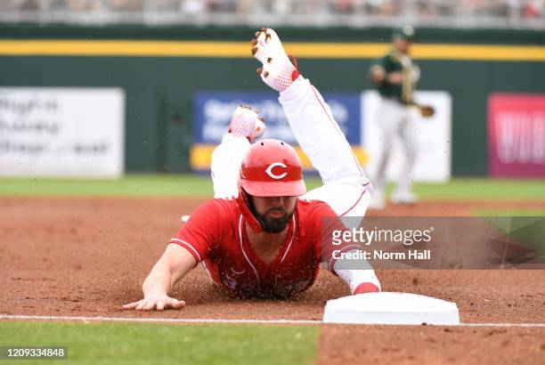 Jesse Winker of the Cincinnati Reds advances to third base on a wild pitch by Mike Fiers of the Oakland Athletics during the third inning of a spring...