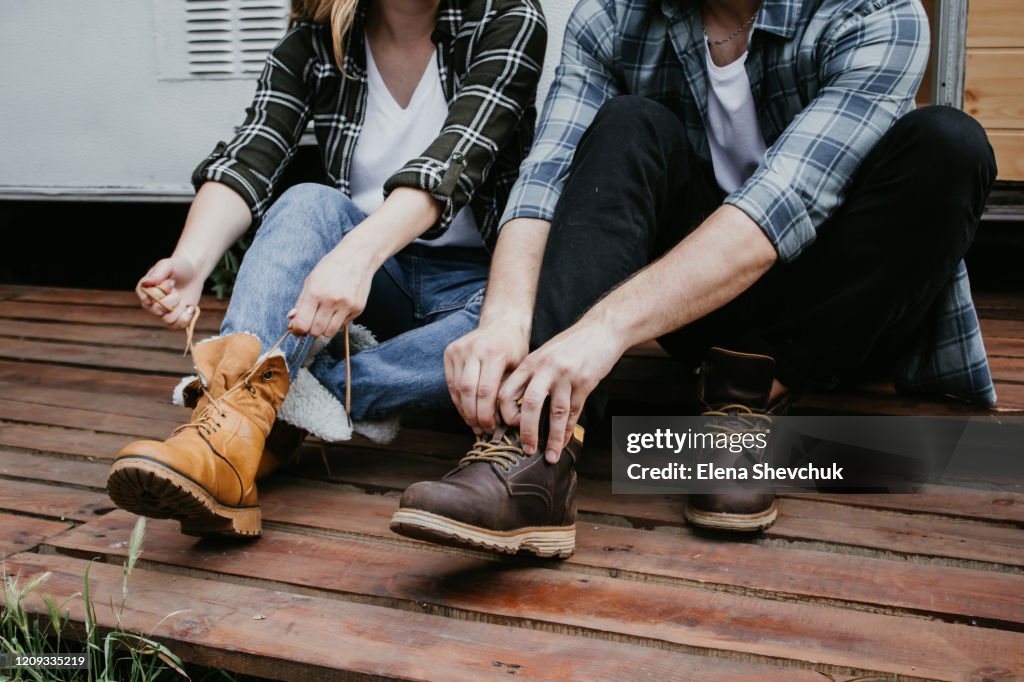 Man's and woman legs in blue jeans and brown boots on wooden floor