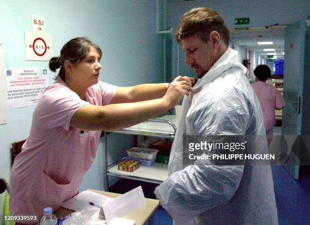 Une infirmiére aide un visiteur du service de gastro-entérologie de l'hopital de Lens à mettre une blouse de protection, le 19 Août 2006 avant de se...