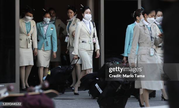 Flight crew from Korean Air, many wearing protective masks, depart the international terminal after arriving at Los Angeles International Airport on...