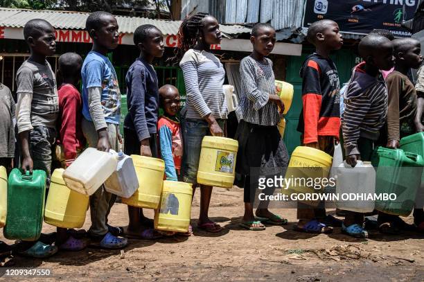Children queue with their jerrycans to fill them with free water distributed by the Kenyan government at Kibera slum in Nairobi, Kenya, on April 7,...