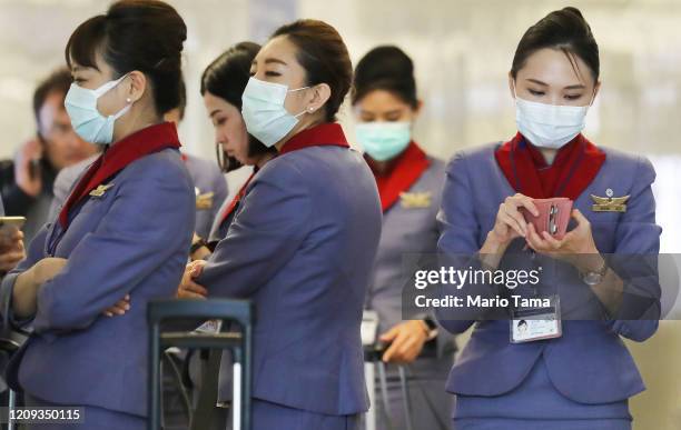Flight crew from China Airlines, wearing protective masks, stand in the international terminal after arriving on a flight from Taipei at Los Angeles...