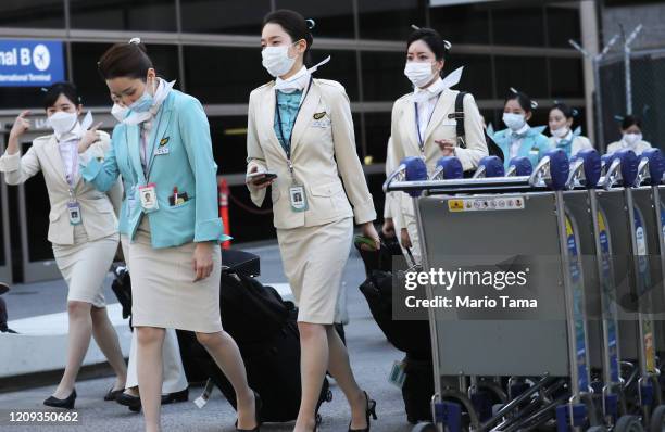 Flight crew from Korean Air, many wearing protective masks, depart the international terminal after arriving at Los Angeles International Airport on...