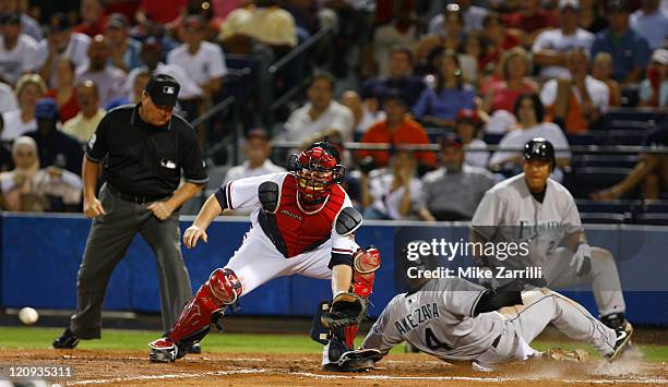 Atlanta Braves C Brian McCann awaits a late throw from the outfield while Florida Marlins SS Alfredo Amezaga slides home during the game between the...