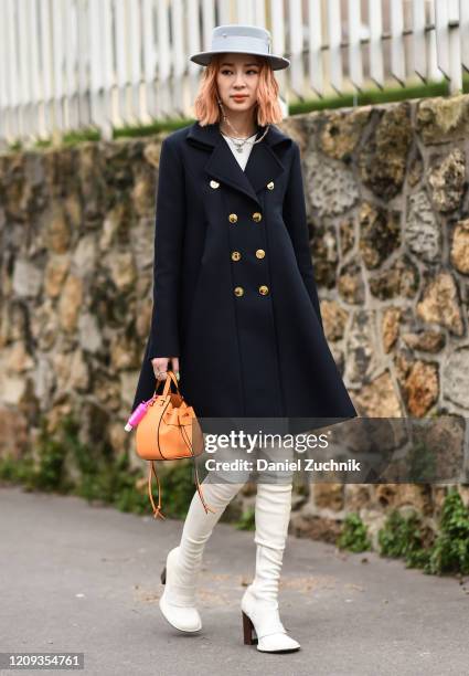 Irene Kim is seen wearing a Loewe coat, gray hat, white boots and Loewe bag outside the Loewe show during Paris Fashion Week: AW20 on February 28,...