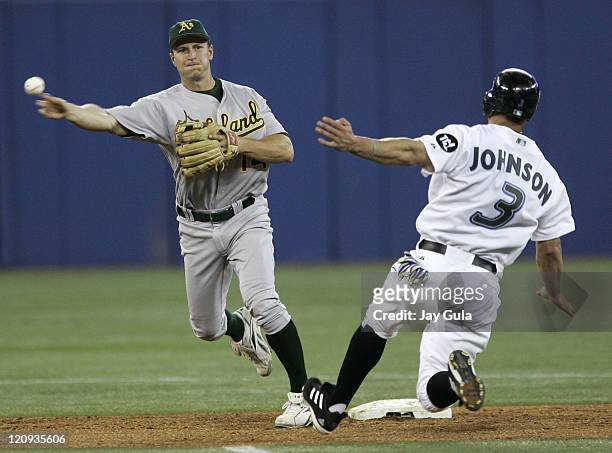Oakland A's 2B Mark Ellis throws to first base to complete a double play over sliding Toronto Blue Jay Reed Johnson in MLB action at Rogers Centre in...