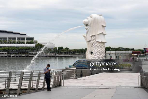 Man wearing a protective face mask uses his phone at the Merlion Park in the Marina Bay area on the day a 'circuit breaker' takes effect on April 7,...