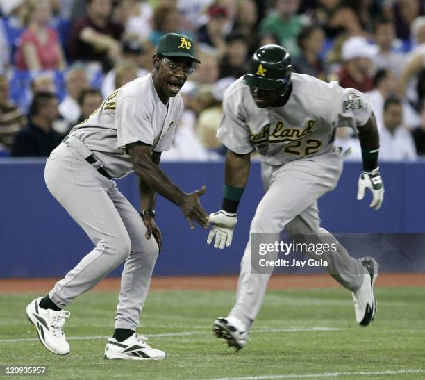 Oakland A's 3B coach Ron Washington gives an enthusiastic low five to Milton Bradley after Bradley hit his 10th home run of the season against the...