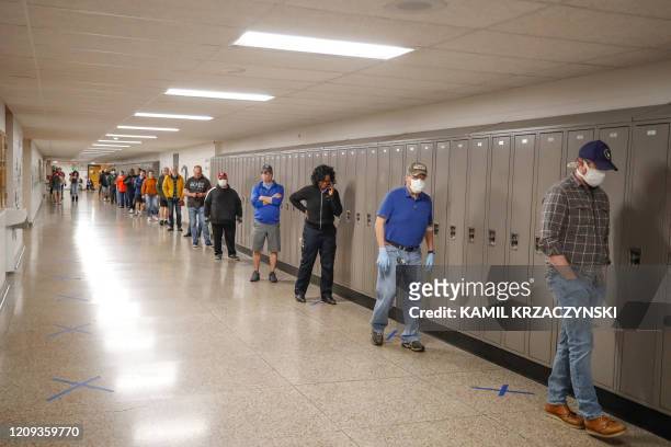 People wait in line to vote in a Democratic presidential primary election outside the Hamilton High School in Milwaukee, Wisconsin, on April 7, 2020....