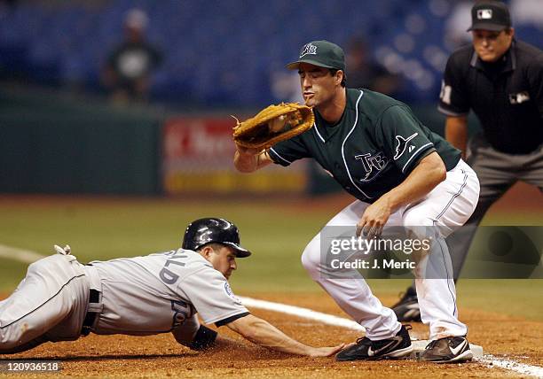 Toronto shortstop John McDonald slides safely back to first as Tampa Bay's Travis Lee takes the throw during Wednesday night's action at Tropicana...