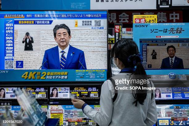 Woman watches a TV as the Japanese Prime Minister Shinzo Abe speaks at a press conference and addressing the citizen through TV. Prime Minister...