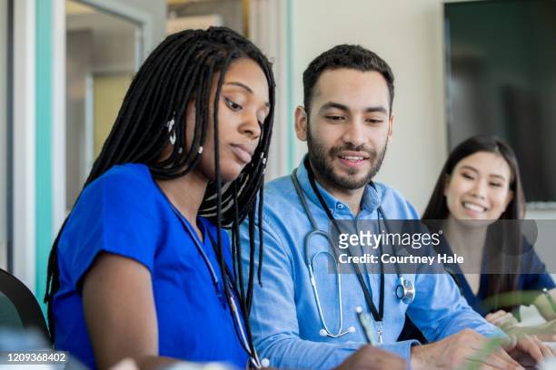 group of medical professionals sitting at a conference table - civilian stock pictures, royalty-free photos & images