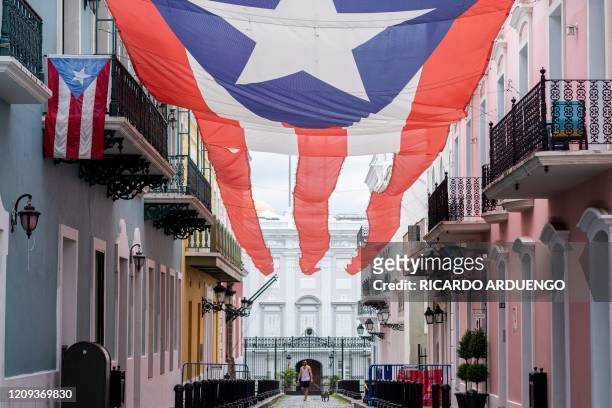 Man walks a dog in front of the Governor's mansion in Old San Juan, Puerto Rico on April 7, 2020. On March 15 Puerto Rico Governor Wanda Vazquez...
