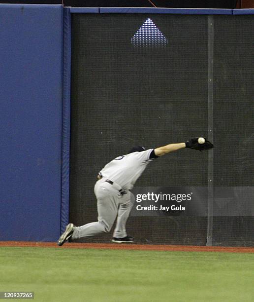 The New York Yankees' CF Bubba Crosby made a valiant effort to catch this ball off the bat of Toronto's Vernon Wells but it glanced off his glove...