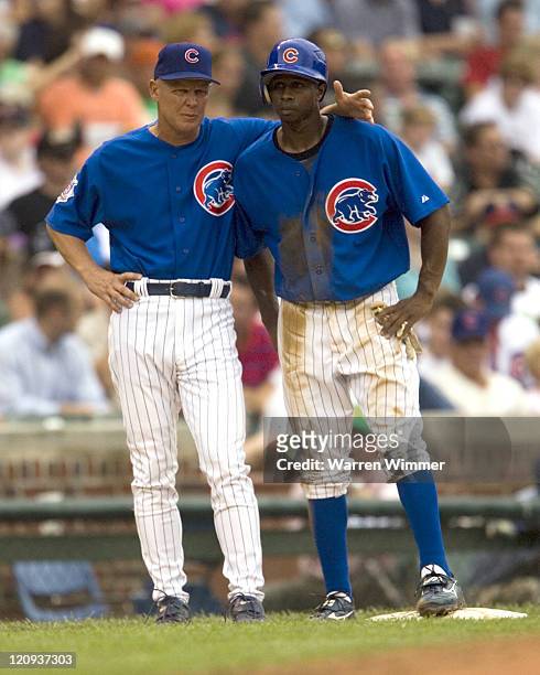 New third base coach, Mike Quade of the Chicago Cubs, confers with Juan Pierre, after Pierre just stole third base during game action at Wrigley...