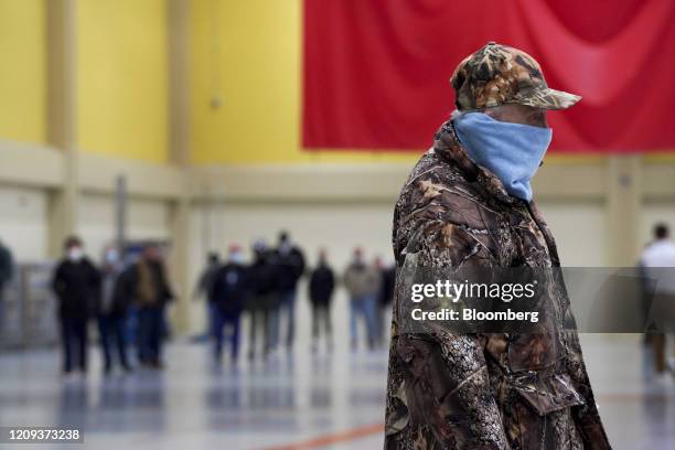 Voter wearing a protective mask stands in line to cast a ballot at a polling station in Milwaukee, Wisconsin, U.S., on Tuesday, April 7, 2020....