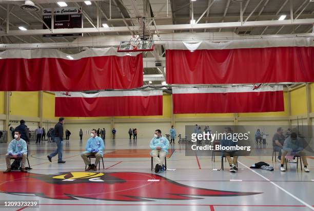 Election volunteers wearing protective gear sit at a distance from on another at a polling station in Milwaukee, Wisconsin, U.S., on Tuesday, April...