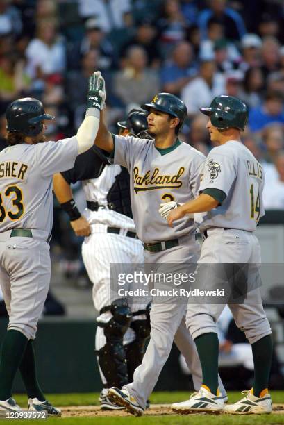 Oakland Athletics' 3rd Baseman, Eric Chavez, is greeted at home plate by teammates, Steve Swisher and Mark Ellis after hitting a 3rd inning 3-run...