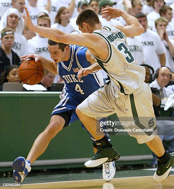 Duke's J.J. Redick rushes the ball upcourt along the sideline in the second half while Spartan Tim Bograkos plays hard defense.