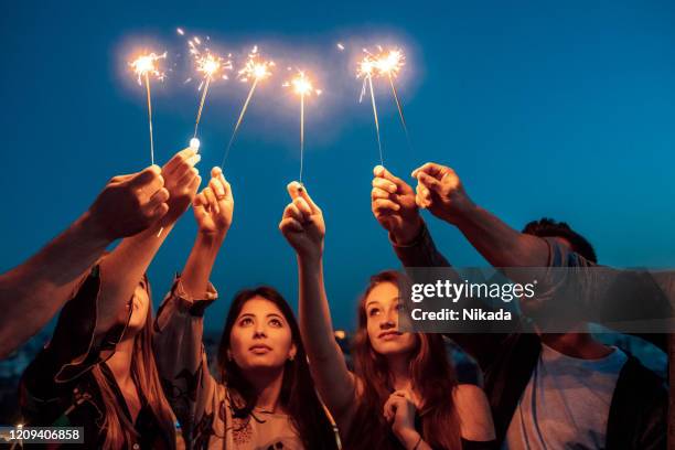 people hands holding sparklers against sky. - multicultural gala an evening of many cultures stock pictures, royalty-free photos & images
