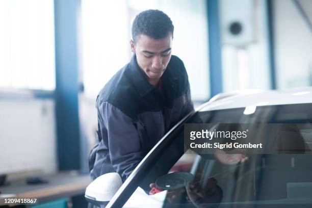 workman fixing car windshield in workshop - parabrisas fotografías e imágenes de stock