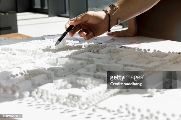 close up of young architect pointing at architectural model. - architekturmodell stock-fotos und bilder