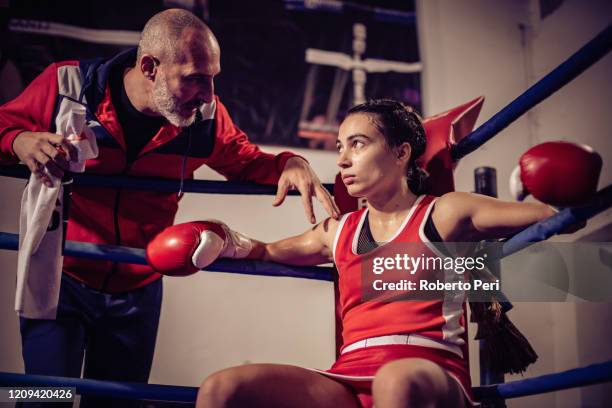 boxing coach talking to female boxer sitting in boxing ring. - boxing trainer stock pictures, royalty-free photos & images