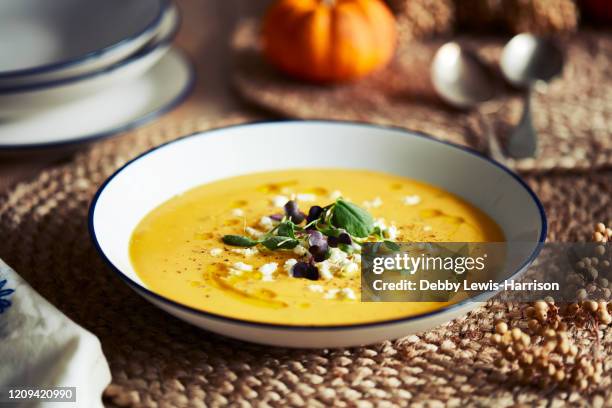 high angle close up of bowl of pumpkin soup with garnish on rustic place mat. - soupe de légumes photos et images de collection