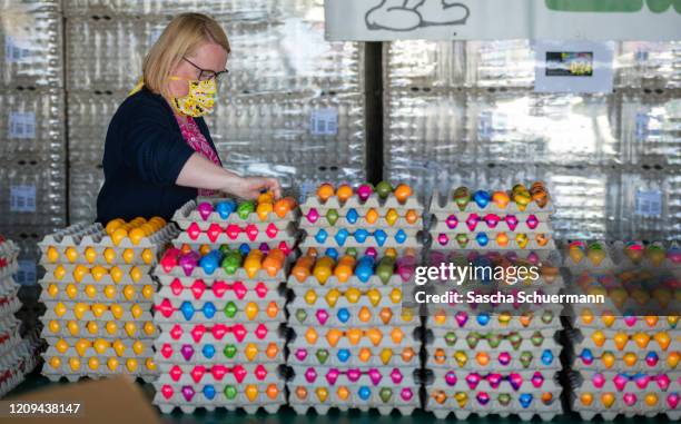 Customer wearing a protective face mask and collect colored Easter eggs at the Landwirt Baumeister egg farm prior to Easter at the coronavirus crisis...