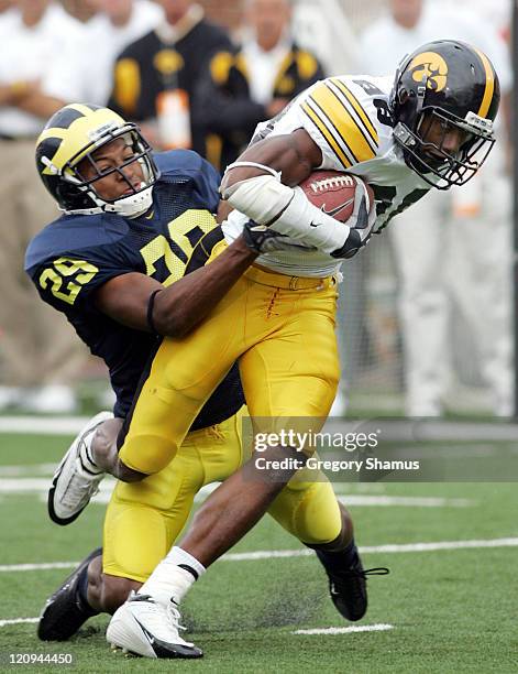 Iowa's Clinton Solomon can't escape the tackle of Michigan's Leon Hall during third quarter action at Michigan Stadium on September 25, 2004....