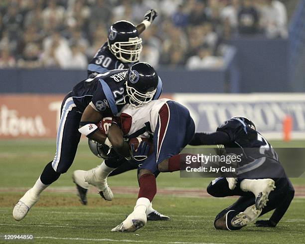 Kerry Watkins of the Montreal Alouettes is tackled by Orlondo Steinauer of the Toronto Argonauts in Canadian Football League action at Rogers Centre...