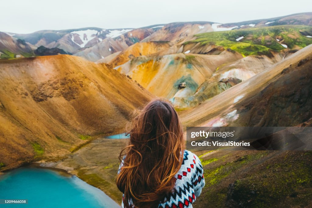 Viaggiatore donna godendo della vista di pittoresche montagne arcobaleno colorate e lago turchese nel deserto