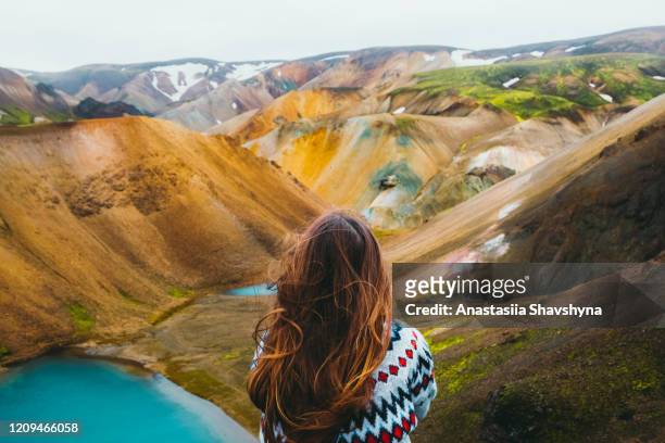 de reiziger die van de vrouw geniet van de mening van schilderachtige kleurrijke regenboogbergen en turquoise meer in de wildernis - landmannalaugar stockfoto's en -beelden