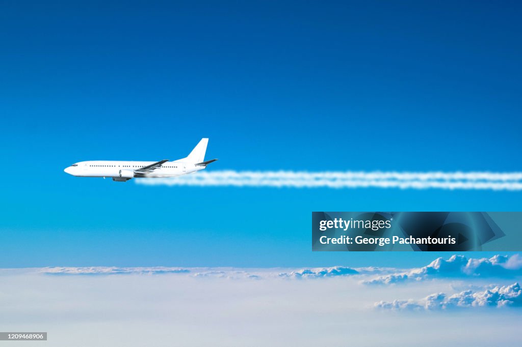 Airplane flying above the clouds leaving a smoke trail