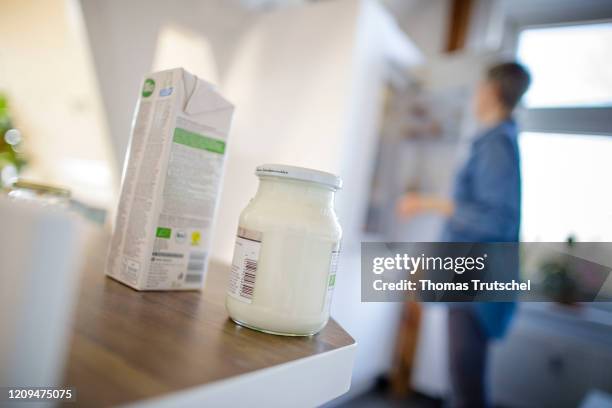 Berlin, Germany Symbolic image on the subject of dairy products. A package of milk and a glass of yoghurt are standing on a kitchen cupboard. In the...